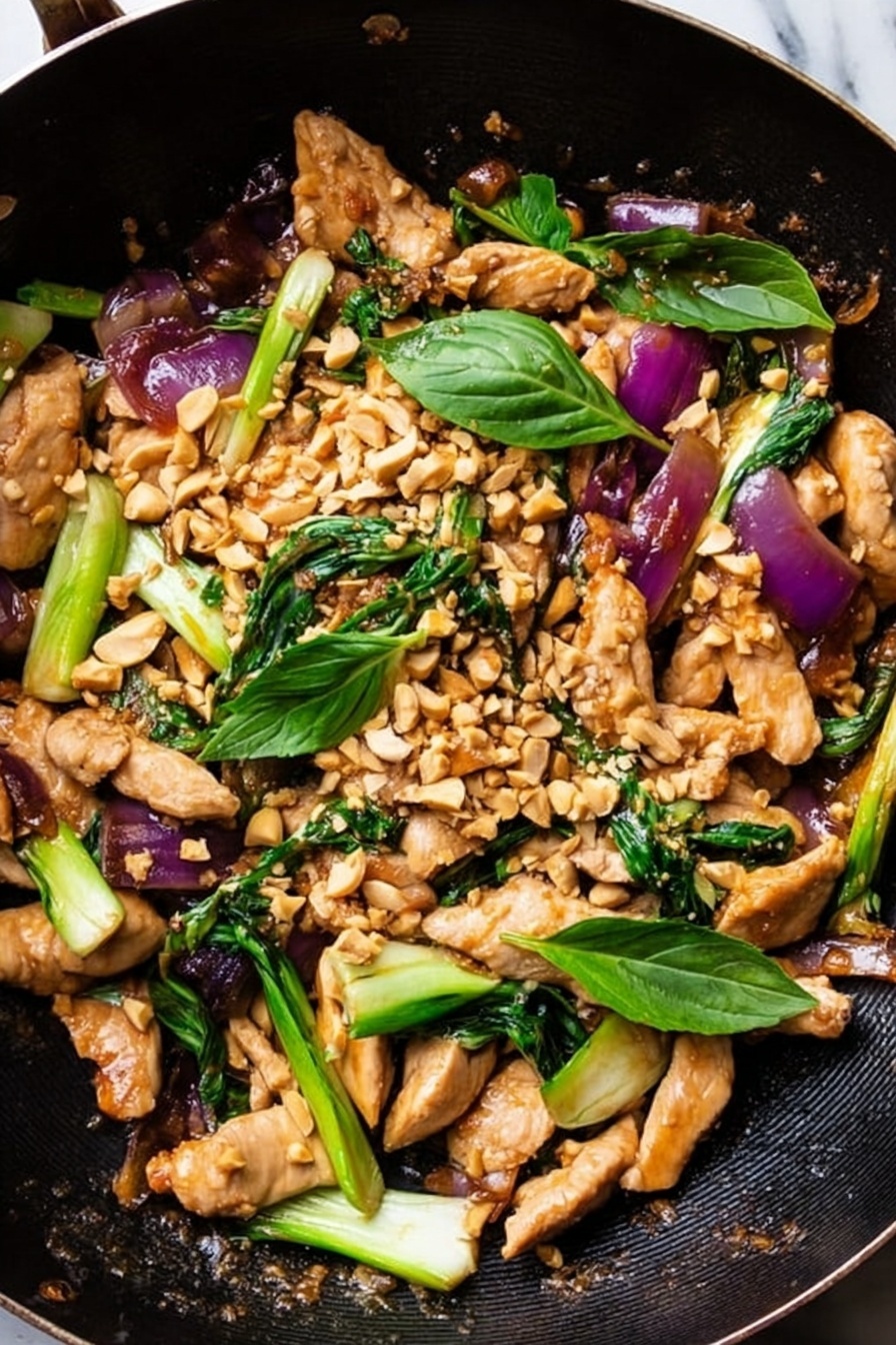 A black wok is filled with a colorful stir-fry showing three main layers: at the bottom, a sauce coating the surface with a shiny texture, on top, long light brown cooked strips of tofu or chicken mixed with bright green bok choy pieces and purplish-red slices of onion. Scattered over the top are many tan crushed peanuts and fresh green basil leaves, adding texture and brightness. The overall look is fresh and vibrant, with varied shapes and colors. The photo taken with an iphone --ar 2:3 --v 7