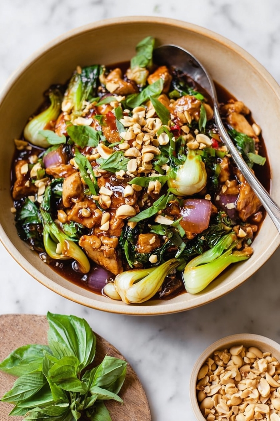 The dish is served in a round, light brown bowl filled with a colorful mix of sliced light pink meat pieces, bright green leafy vegetables, and chunks of pale green vegetables. On top, a generous layer of chopped light brown nuts and fresh green basil leaves adds texture and color. The bowl contains a glossy, dark brown sauce that coats the ingredients well. A silver spoon stands in the bowl, and in the background, there is a white bowl with plain white rice peeking in from the top right corner. The setting is on a white marbled surface, with a small bowl of chopped nuts nearby and a few fresh basil leaves scattered on the surface. Photo taken with an iphone --ar 2:3 --v 7