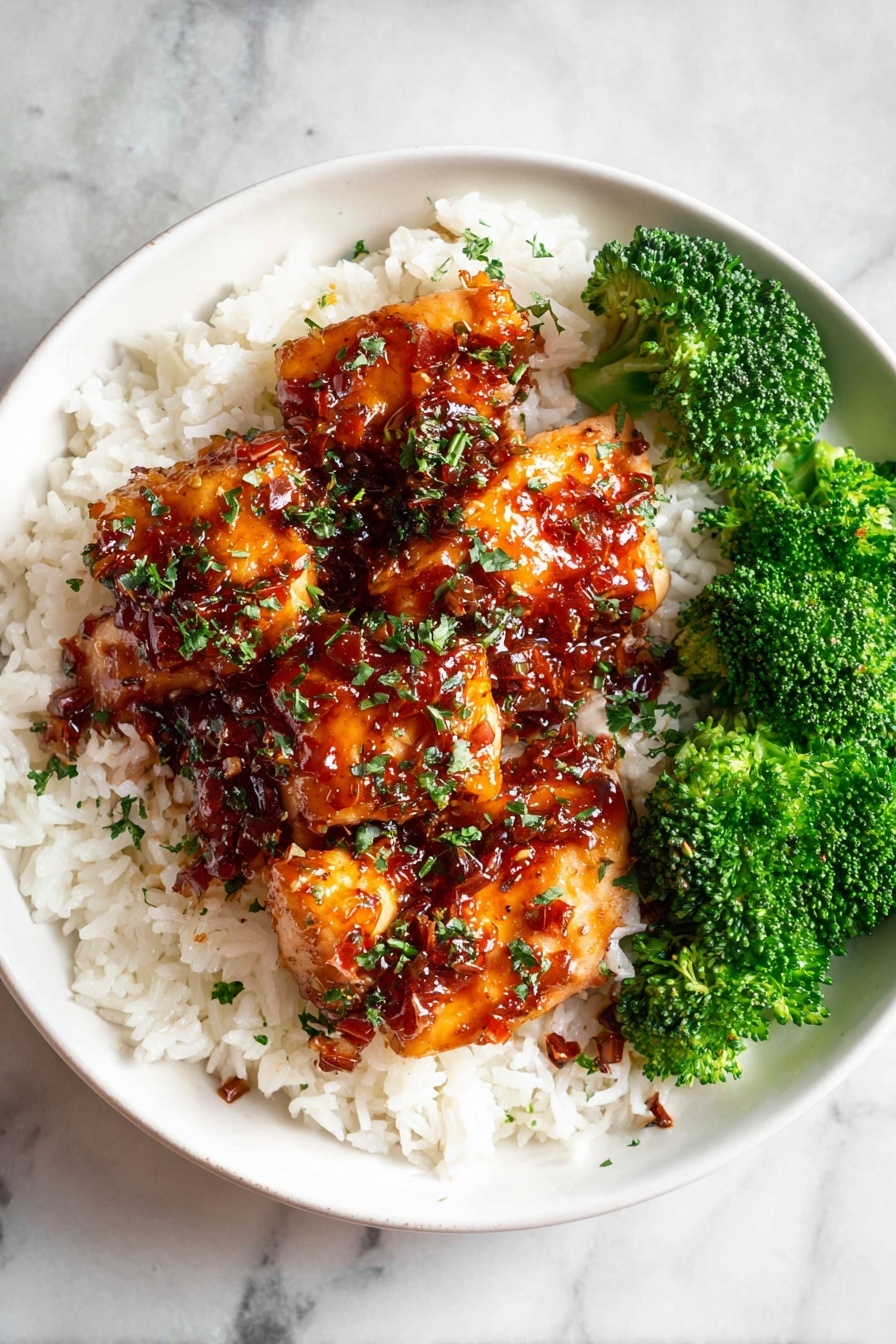 A white bowl sits on a white marbled surface filled with three layers: the bottom layer is fluffy white rice spread evenly; the middle layer has several pieces of orange-brown glazed chicken with a shiny sauce and small red spice flakes, sprinkled with chopped green herbs; the top right section contains bright green broccoli florets that add a fresh, textured contrast. Photo taken with an iphone --ar 2:3 --v 7