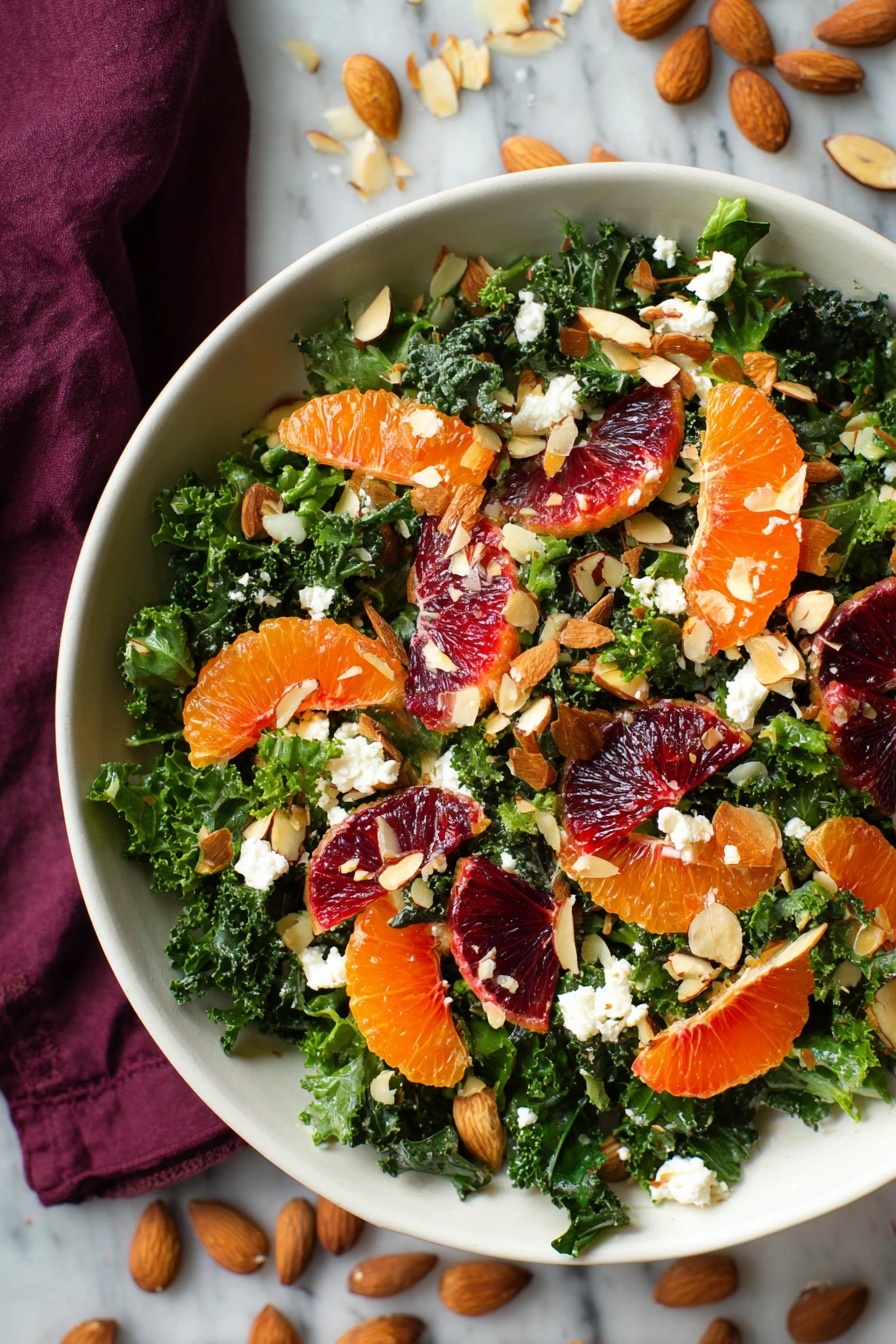 A white bowl is filled with a fresh salad showing bright green chopped kale as the base layer. On top of the kale, there are scattered slices of deep red blood orange and small orange tangerine segments. Thin, light brown toasted almond slices and small chunks of white cheese are sprinkled evenly over the salad. The bowl sits on a white marbled surface with a dark cloth partially visible around the edges. photo taken with an iphone --ar 2:3 --v 7