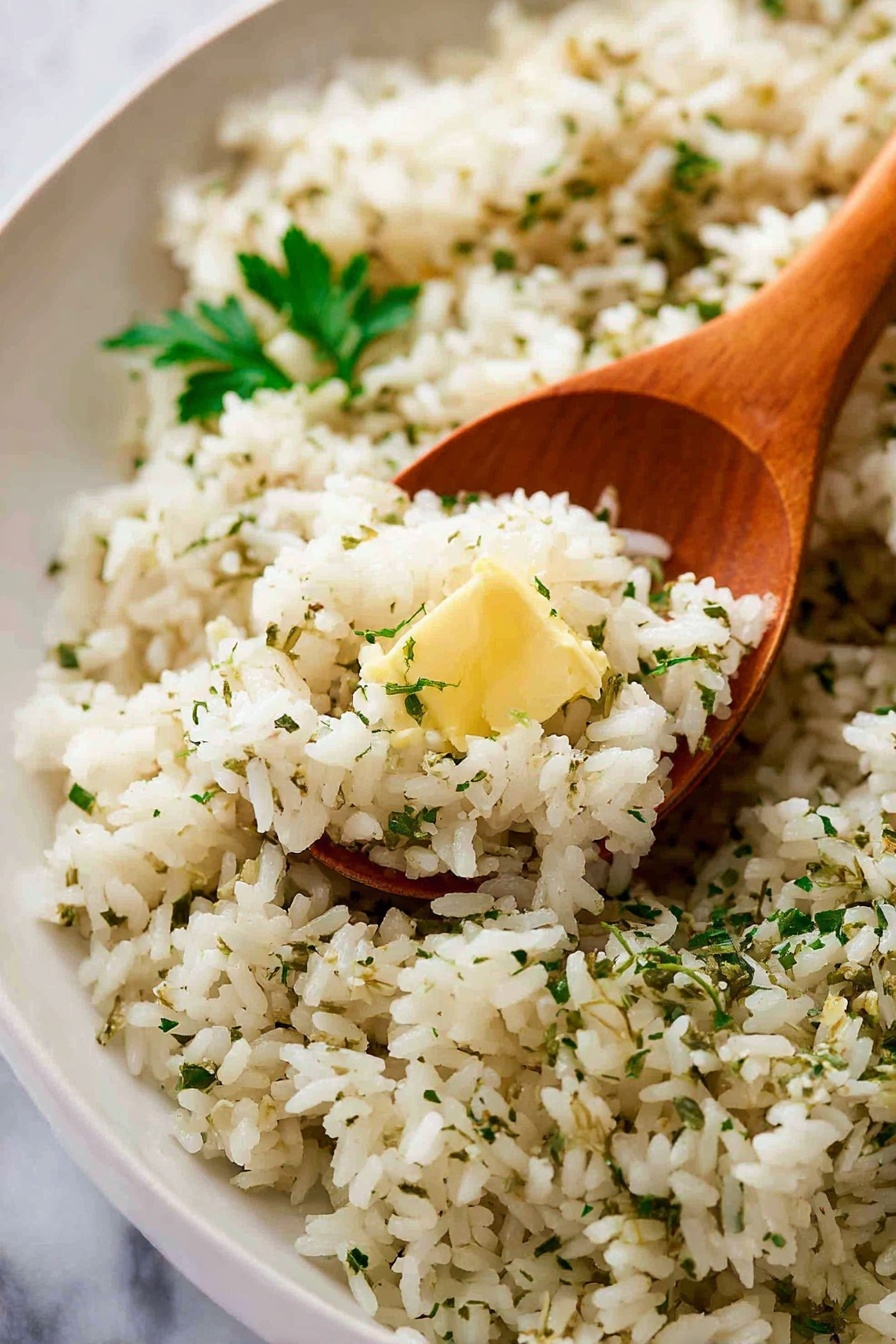 The image shows a large white oval plate filled with a mound of cooked rice mixed with herbs and spices, giving the rice a light brown color with specks of green and black. There is a small spot of melted butter visible near the center of the rice, and chopped fresh parsley is sprinkled evenly on top. On the right side of the plate, a wooden spoon is resting partially in the rice. The background has a soft, light green cloth and the surface is white with a marbled texture. photo taken with an iphone --ar 2:3 --v 7
