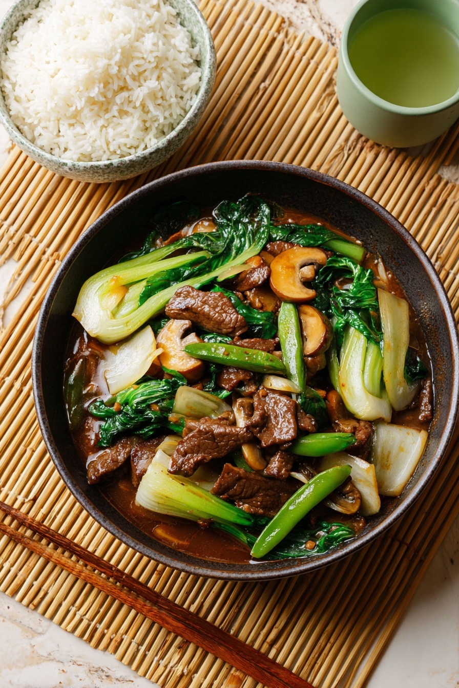 The image shows a close-up of a dark brown bowl filled with a stir-fried dish. The dish has two main layers: at the bottom are glossy pieces of dark brown meat covered in sauce, and on top are bright green snap peas, white and light green bok choy leaves, dark green kale, and brown mushrooms mixed with the sauce. The bowl is placed on a bamboo mat, and in the background, there is a small white bowl of white rice with blue patterns and a white ceramic cup with green tea, all on a white marbled surface. Photo taken with an iphone --ar 2:3 --v 7
