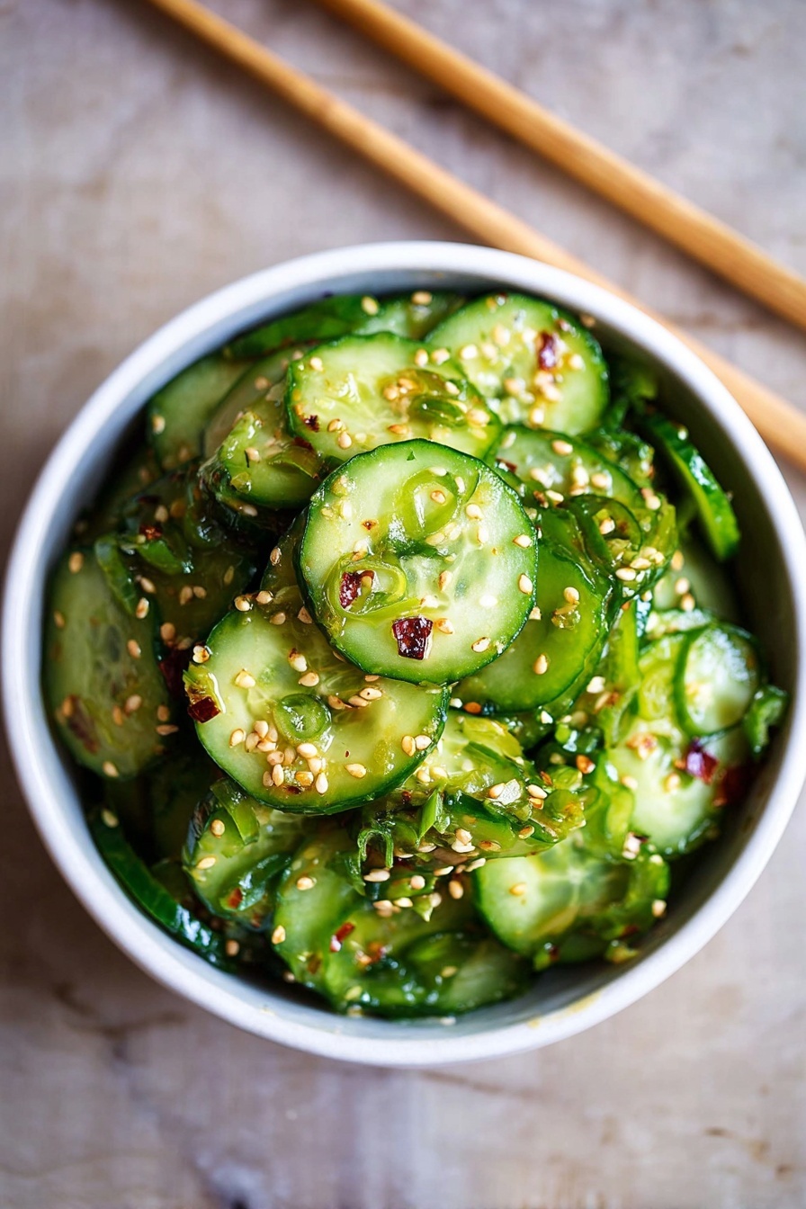 A white bowl filled with thinly sliced green cucumbers, layered in a slightly messy pile. The cucumbers are coated with small white sesame seeds and bits of finely chopped green onions. The green cucumber slices show their juicy and fresh texture with some seeds visible inside. The bowl sits on a white marbled surface with a pair of wooden chopsticks placed diagonally behind it. The overall look is fresh and vibrant, focusing on the crisp texture of the cucumbers and the sprinkle of sesame seeds. photo taken with an iphone --ar 2:3 --v 7