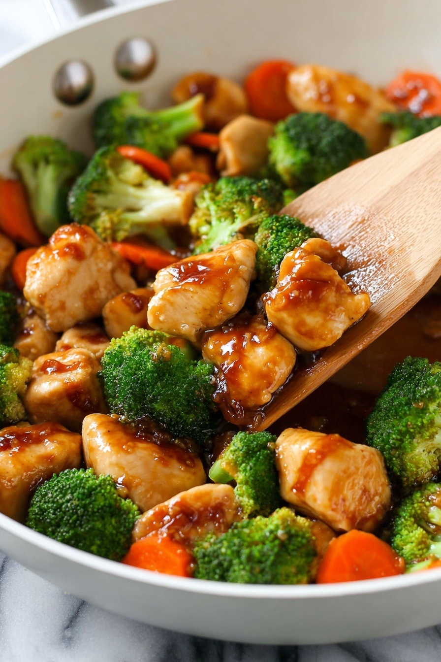 The image shows a white pan filled with pieces of cooked chicken coated in glossy brown sauce, mixed with bright green broccoli florets and some orange carrot slices. A wooden spatula is lifting a portion, showing the shiny texture of the sauce on the tender chicken chunks and fresh vegetables. The background has a white marbled texture. photo taken with an iphone --ar 2:3 --v 7