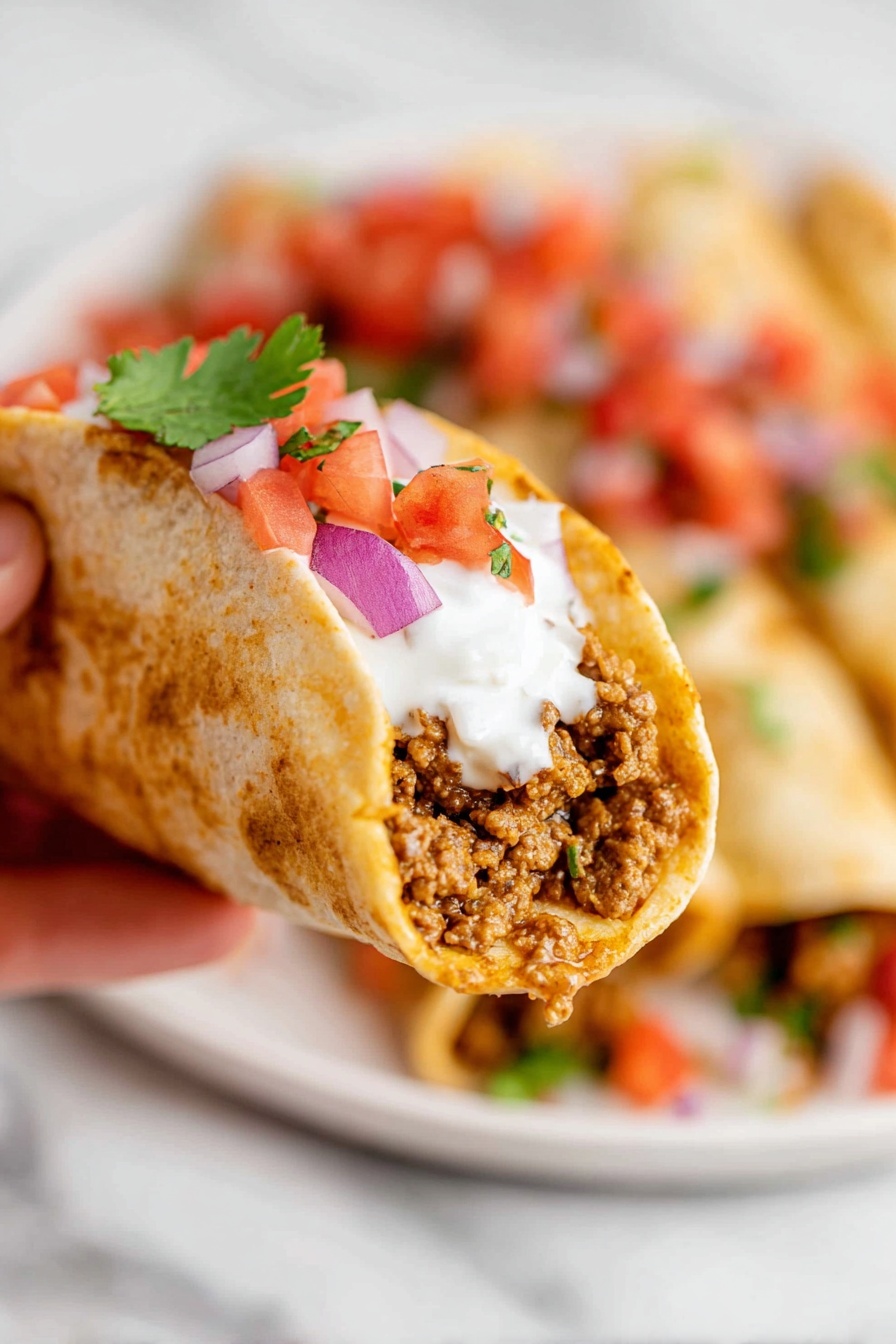 A woman's hand holds a folded wrap showing three layers: the outer light golden-brown soft tortilla, a middle layer of cooked brown ground meat with some light yellow pieces mixed in, and a topping of white creamy sauce with small red tomato pieces and green herb bits on top. In the blurred white bowl below filled with colorful chopped red tomatoes, purple onions, and green herbs. The background is a white marbled texture. photo taken with an iphone --ar 2:3 --v 7