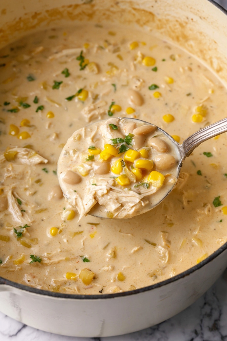 A close-up view of a creamy chicken soup inside a large pot, showing a thick, pale yellow broth with shredded white chicken meat scattered throughout. The soup also contains bright yellow corn kernels and white beans, mixed evenly, with small pieces of green herbs floating on top. The ladle, made of metal, is lifting a scoop of the creamy soup prominently in the center, displaying the soup’s dense texture and mix of ingredients. The pot is set over a white marbled surface, and the scene is softly lit to show the smooth, rich texture of the soup. photo taken with an iphone --ar 2:3 --v 7